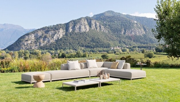 beige stoffen loungeset met tafel op het gras met berglandschap