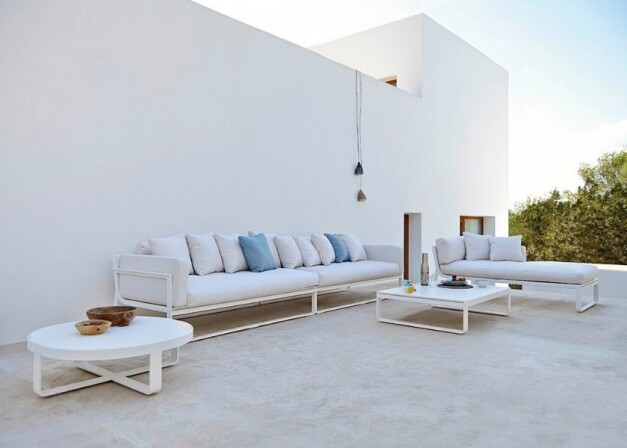 gandiablasco flat lichte loungeset met tafels langs een groot wit gebouw