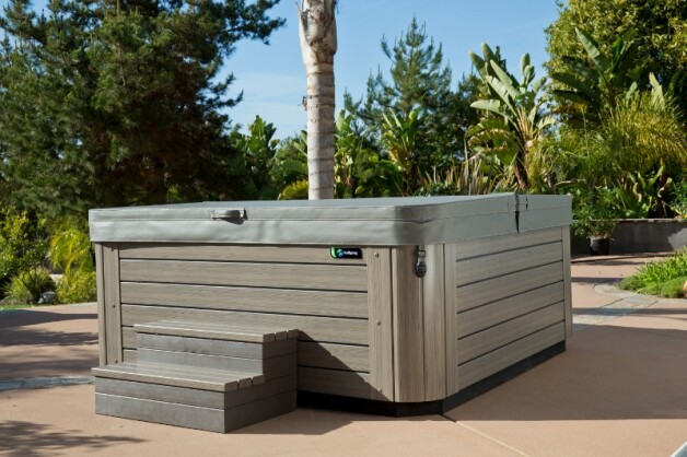 beige jacuzzi in tuin op stenen vloer schuin zijaanzicht