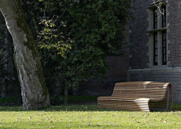 b&b italia titikaka houten zitbank langs een gebouw muur en een boom in de schaduw