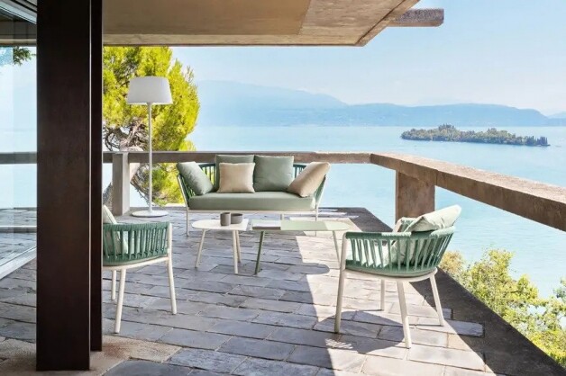 witte loungezetel met licht blauw kussen en stoelen op een terras met zeezicht