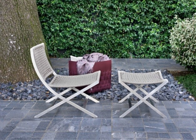 outdoor beige loungestoel op stenen vloer met mand met dekens zijaanzicht