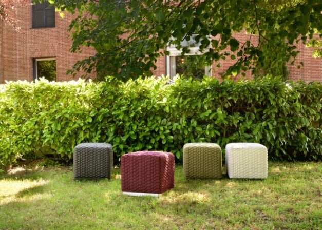 gevlochten krukjes in verschillende kleuren langs een groene haag op het gras