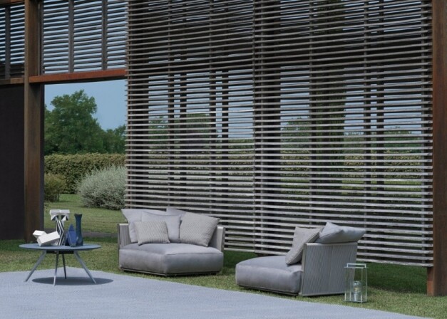 outdoor grijze loungeset met grijze tafel op gras langs een grote muur