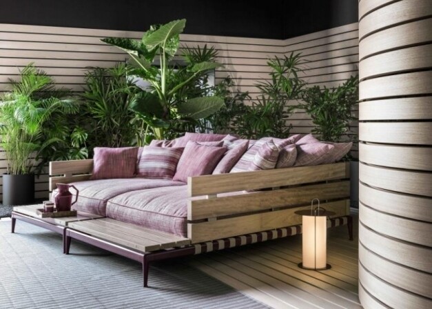 ligbed met roze kussens met planten rond in een relax ruimte