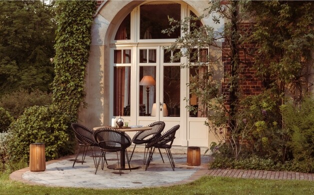 vincent sheppard roxy dining chair camel zwart stoelen met tafel langs een grote deur van een huis op het stenen terras
