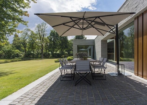 tuuci ocean master parasol grijs over een tuintafel met stoelen heen zijaanzicht