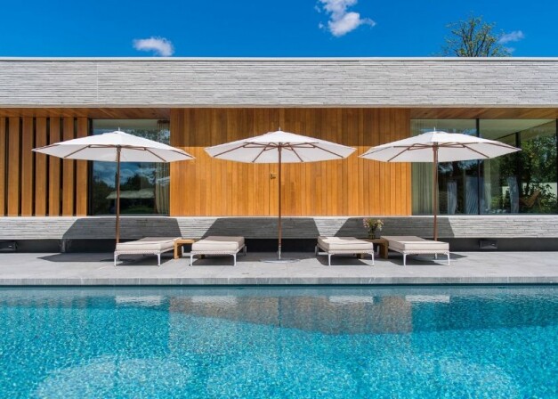 tuuci plantation witte parasols boven beige ligbedden langs het zwembad